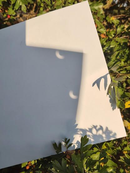 Images of the light going through a hole punched piece of card onto another. You can see the banana shaped crescent.