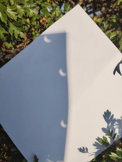 Images of the light going through a hole punched piece of card onto another. You can see the banana shaped crescent.