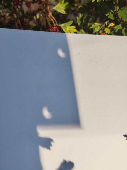 Images of the light going through a hole punched piece of card onto another. You can see the banana shaped crescent.