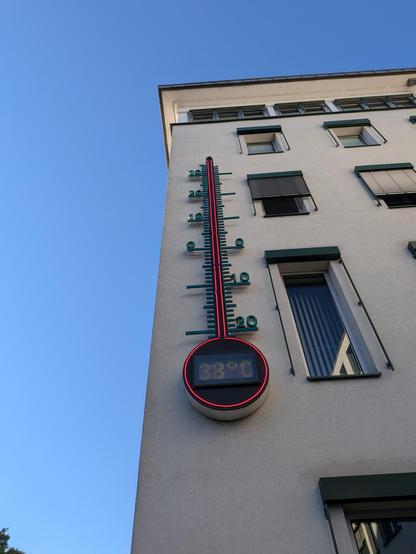 Huge thermometer on the side of a building showing 38°C with it being the maximum on the scale.