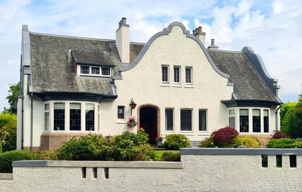 An Art Deco style house with a large and ornate curved gable over the front door.