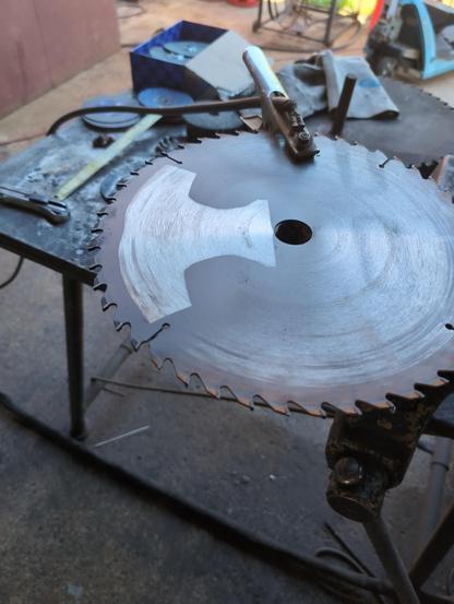 An old saw blade with a lighter imprint outlining my knife blade. It's an ulu-style knife, so curved blade with the grip centered above.
