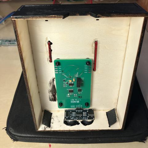 inside of a laser cut plywood box, with the circuit board mounted in it. the outside is painted black.