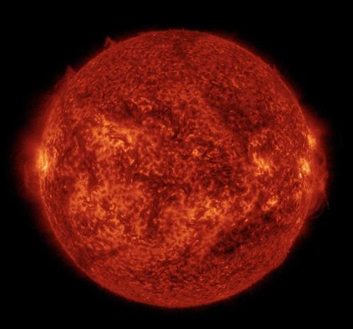 Die ganze erdzugewandte Seite der Sonne in orangeroter Farbe. Die Sonne sieht hier wie eine heiß glühende Kugel aus. Auf Äquatorhöhe links und auch gegenüber rechts am Rand einige hellere Gebiete, als würde es da aus dem Inneren hervorscheinen. Drumherum das Schwarz des Weltalls.