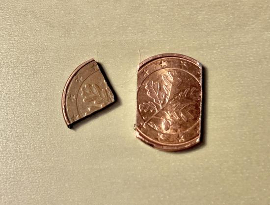 The quarter of a 1c coin, and another coin where only about a fifth of the total has been filed away.