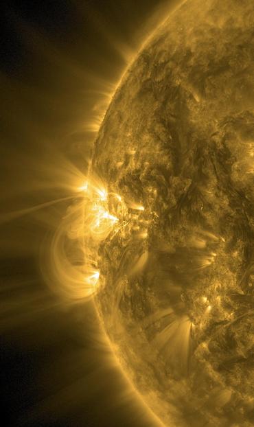Der linke Rand der Sonne in starker Ausschnittvergrößerung und gelber Farbe. Um die Zeigerposition neun Uhr herum vier bis fünf nahezu weiße Stellen, von denen leuchtend helle Sonnenmaterie ins schwarze Weltall strömt. Teils breitet sie sich fächerförmig aus, teils bildet sie den Magnetfeldern folgend gewaltige Bögen, die zur Sonne zurückführen.