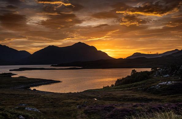 A golden sunrise over mountains and sea.