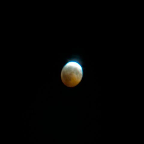A motion blurred dark moon with a bright silver crescent at the top, covering maybe 10% of the moon but well outshining the rest of it.