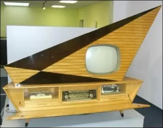 The cabinet resembles a cross between a sailboat and a spaceship. It is made from blonde maple and dark wood with a high-gloss finish.