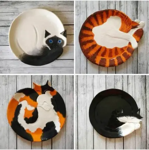 Four curled up cats, as ceramic plates:

Siamese: A sleek white plate featuring a dark face and striking blue eyes.

Orange Tabby: Bold tiger-striped curves wrapping around the dish.

Calico / Tortoiseshell: patches of orange, black, and white.

Tuxedo: A pure black body accentuated by a white chin and chest.