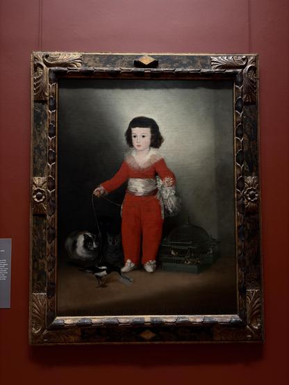 A young boy dressed in red with a white sash, holding a string of a black-and-white cat and a bird, with two other cats and a birdcage nearby.

Goya (Francisco de Goya y Lucientes)
Spanish, Fuendetodos 1746-1828 Bordeaux
Manuel Osorio Manrique de Zuñiga (1784-1792),
1787-88
Oil on canvas
Outfitted in a splendid red costume, the son of the count and countess of Altamira is shown between a cage of finches and three wide-eyed cats who appear captivated by the boy's pet magpie. In its beak the magpie holds Goya's calling card and signature. Goya may have intended this cast of animals as a reminder of the frail boundaries that separate the child's world from the forces of evil, or as a commentary on the fleeting nature of innocence and youth. Manuel died only a few years after his portrait was painted, at the age of eight.
The Jules Bache Collection, 1949 (49.741)