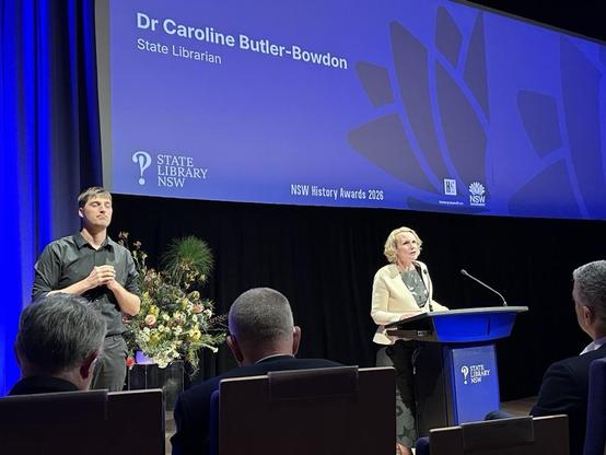 A woman addresses a crowd from behind a lectern