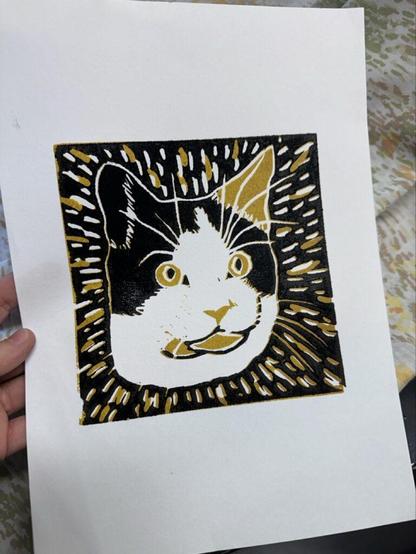 A linocut print of a tortoiseshell cat in black and gold.