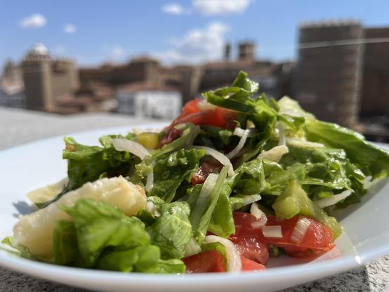 A plate of salad in front of a backdrop of the medieval buildings of the town centre.