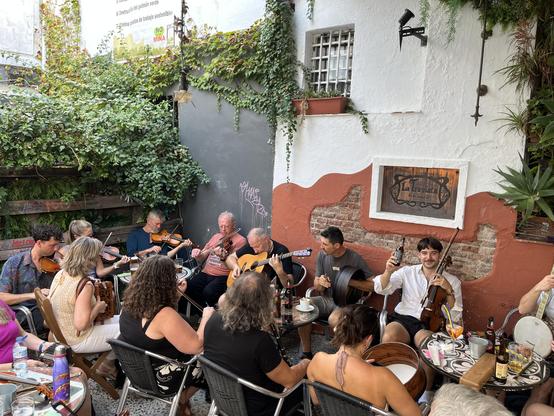 A long table outside with loads of musicians, including my mate Liam who is raising a bottle.