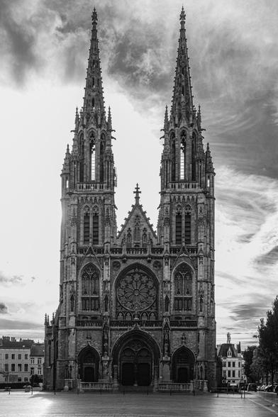 Das schwarz-weiß Foto zeigt eine große Kirchen mit 2 hohen Türmen in der Frontansicht. Der Himmel ist von Schleierwolken durchzogen.