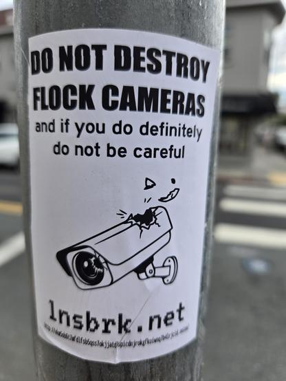 A sticker for lnsbrk.net. It depicts a securicam with a hole through the casing. There are URLs for the regular net and the Tor network. 

It reads "Do not destroy Flock cameras. And if you do, definitely do not be careful." Nudge nudge, wink wink.