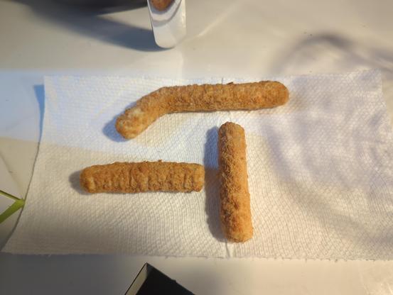 three mozzarella sticks on a paper towel. one is twice as long as it should be and slightly bent, so it looks like a radical symbol. the sticks are arranged to look like the square root of -1