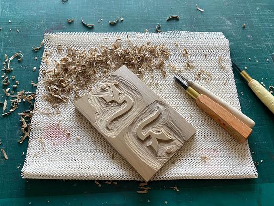 Process shot of the plate being hand-carved, wood chips everywhere.