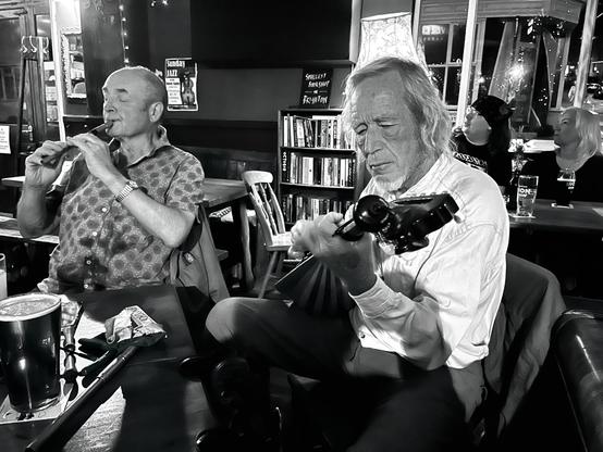 A man playing Greek bouzouki and a man plan playing tin whistle.