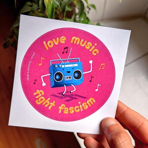 Round illustration on a pink background with a boombox-character dancing happily on a broken swastika. Text around it says „Love music, fight fascism“.