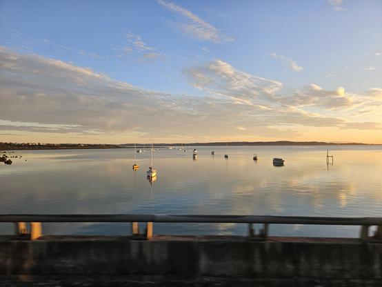 View from the bus of Whau River mouth this fine morning with stratus cloud action, tide in, boats moored, & motorway barrier visible at bottom.
