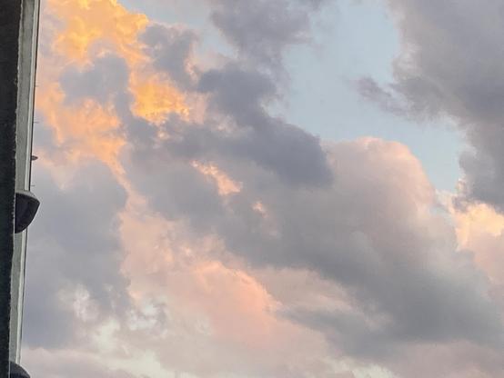 Orange, pink, and lavender clouds with glimpses of pale blue sky. The clouds are very pretty and billowy.