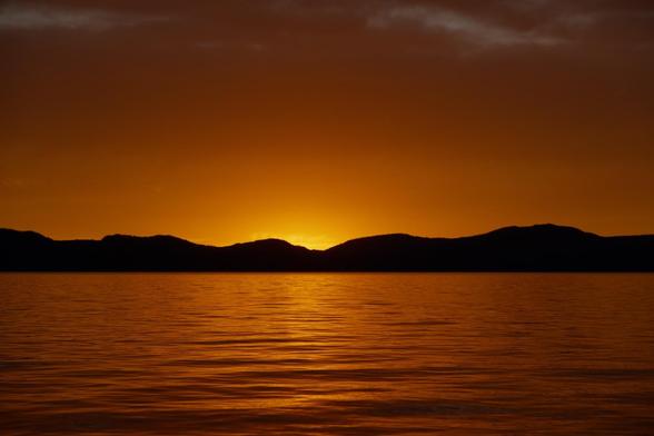 An intense orange sunset, photographed shortly after the sun sank behind a mountain range.