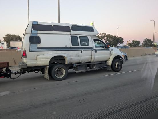 A Ford F650 truck with a camper van rear end grafted on it, driving down the interstate
