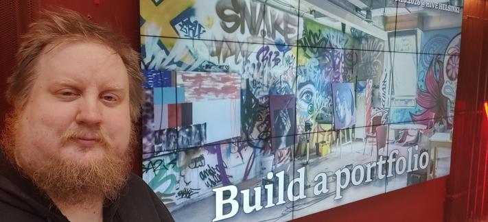 A selfie of Juhis with a slide of art gallery titled Build a portfolio in the background.