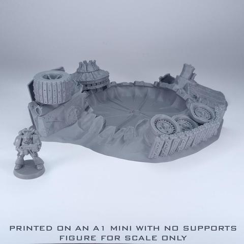 An unpainted grey crater with ruined vehicle parts around it and a figure next to it