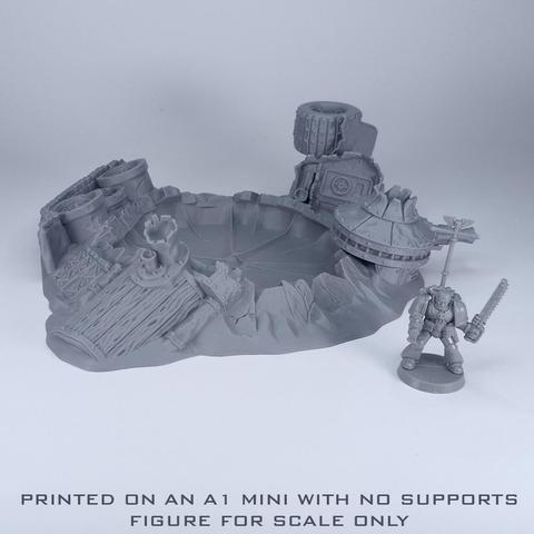 An unpainted grey crater from a different angle with ruined vehicle parts around it and a figure next to it
