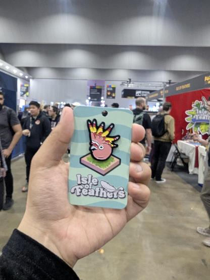 A left hand holding a Pink Cockatoo enamel pin