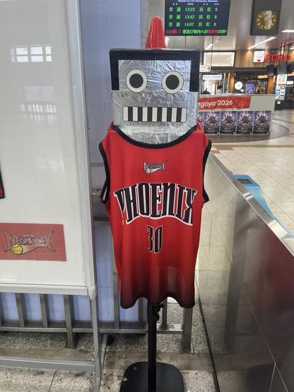 Robot mascot at train station wearing a basketball jersey