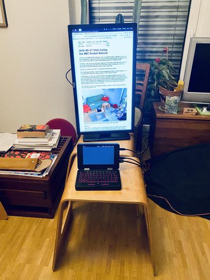 A tiny laptop on a kind of coffee table, behind it a big monitor in portrait orientation. In front of it a cushion to sit on.