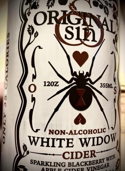 A can of Original Sin White Widow non-alcoholic cider.  To the left of a large illustration of a black widow spider, there is text that reads “120Z”.  To the right of the illustration, “355ML”.
