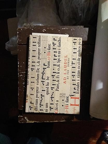 The book, seen from above as it lies on a table ready to be packed up. It's covered in music with red and black calligraphy.