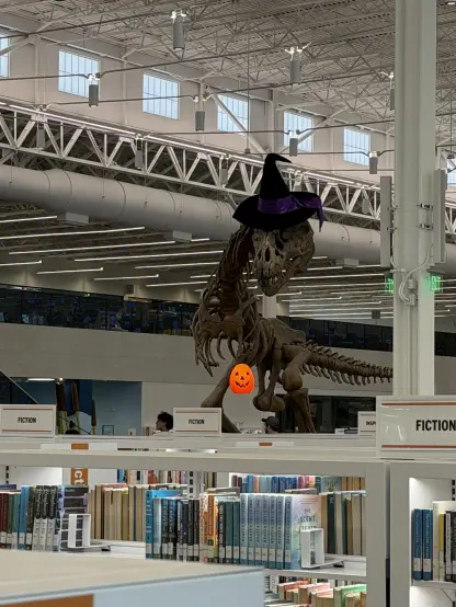A TRex skeleton in a library wearing a witch's hat