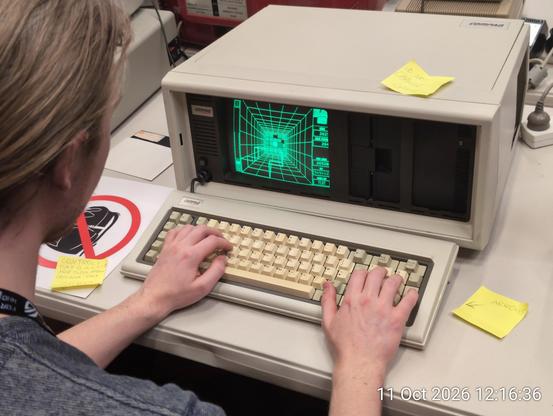 Very old looking desktop computer with integrated green CRT. Playing some kind of top down Tetris?