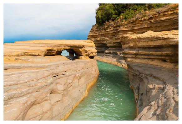Erodierte Sandsteinschichten formen eine bizzarre Küstenlandschaft mit einem natürlichen Wasserkanal.