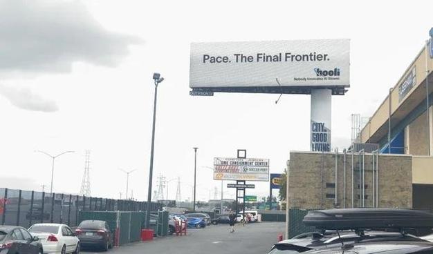 A photograph of a billboard which shows the Hooli logo and reads “Pace. The Final Frontier.”