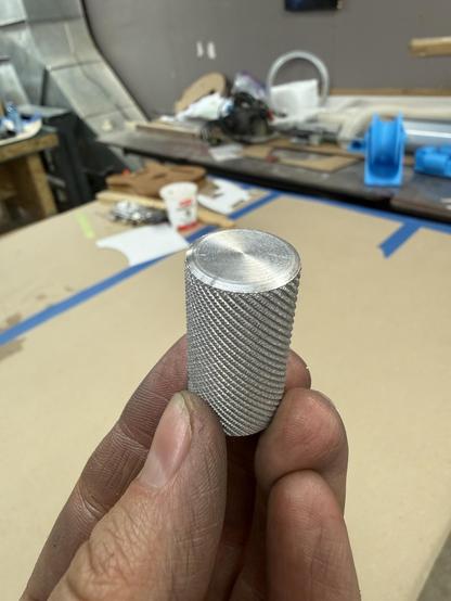 A round aluminum object about 3cm long and 1cm around, with the top faced off and chamfered and the length of it knurled