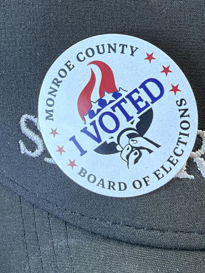Round “I VOTED” sticker on a black golfer’s hat.