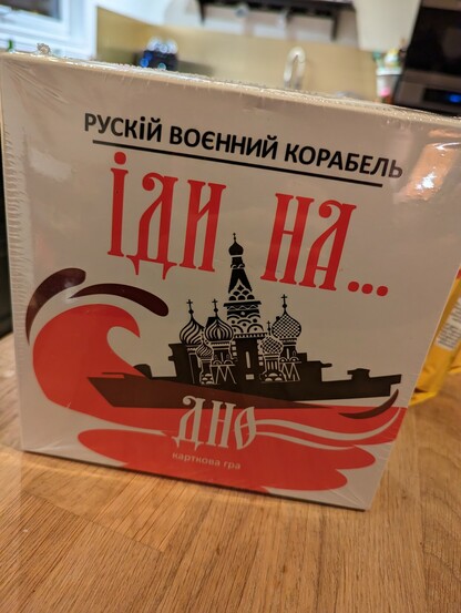 Photo of front of card game box, in Ukrainian; picture of a boat sinking, with the Kremlin aboard