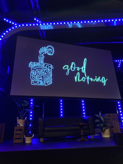 Stage at the beyond Tellerrand conference with a sofa and a screen that says good morning.