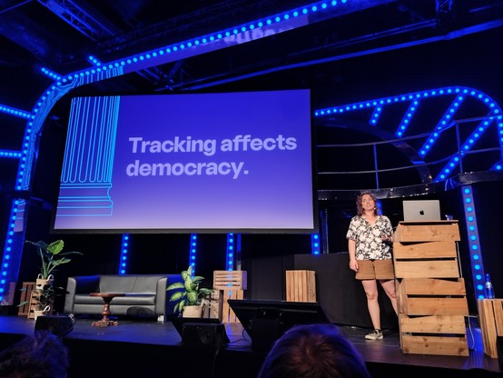 Laura in front of one of her slides, with the text "Tracking affects democracy."