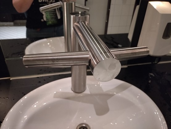 A weird anchor shaped Dyson tap. A sensor in the middle starts water running. If you put two hands under the two side wings, they blow air diagonally down towards the user.