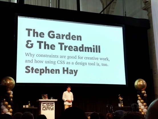 Stephen Hay on stage, his title slide behind him with text:

The Garden & The Treadmill
Why constraints are good for creative work, and how using CSS as a design tool is, too.