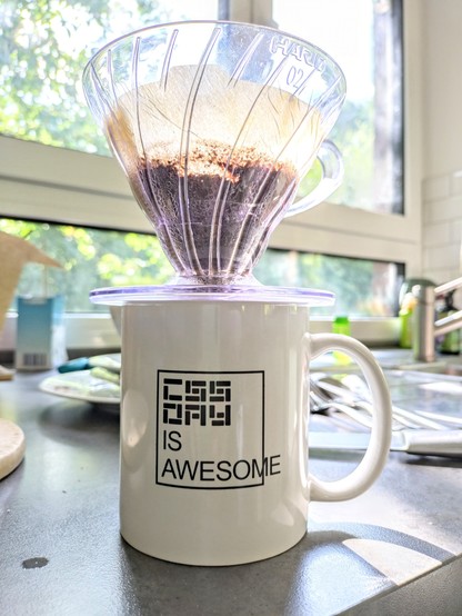 CSS Day mug with a coffee filter funnel atop it.

The logo is the classic box with "CSS IS AWESOME" flowing outside the box, albeit with the CSS Day logo instead of just CSS.