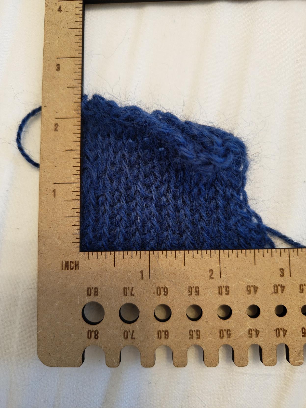 blue yarn tension square on a white background with a ruler overlay